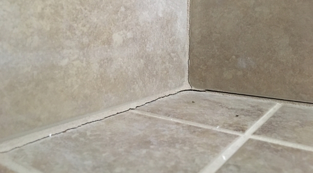 Separating grout at a tile corner in a bathroom shower