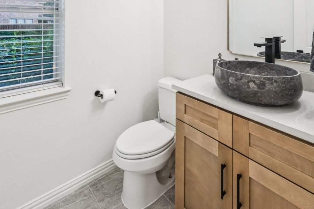 Powder bathroom after painting with bright white walls and new wood vanity