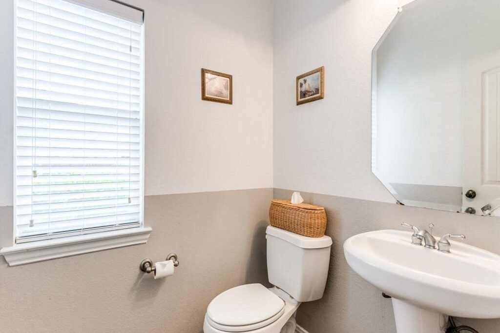 Powder bathroom before painting with two-tone gray walls and pedestal sink