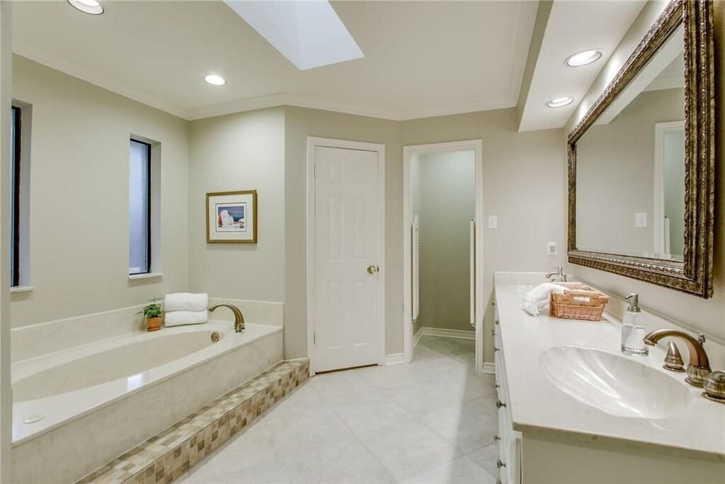 Primary bathroom before painting with beige walls and vanity